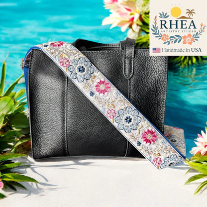 Black handbag with a floral purse strap by RHEA Artistry Studio against a beach background.