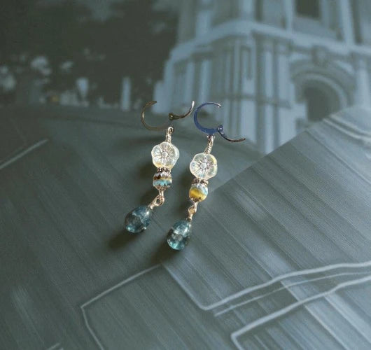 Pair of earrings with gemstones on a textured surface