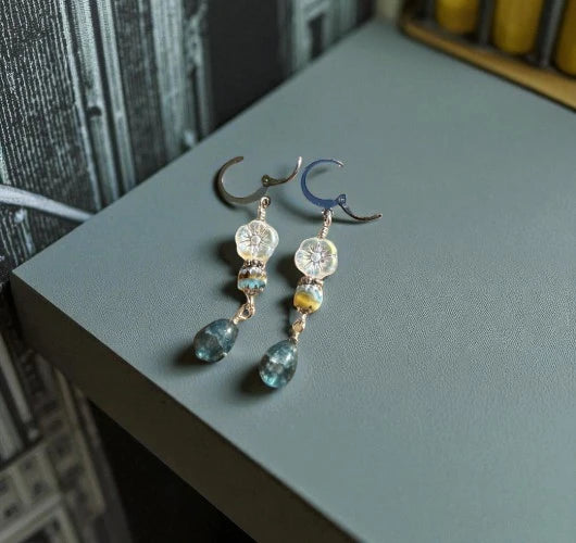 Pair of earrings with gemstones on a gray surface