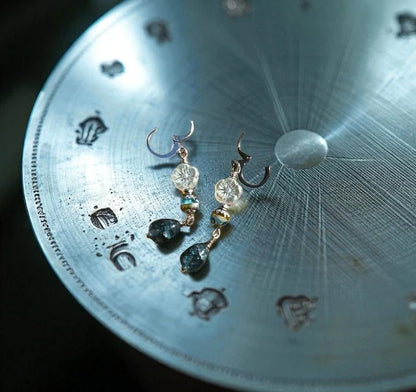 Pair of earrings on a metallic surface with engraved patterns