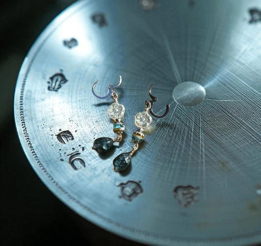Pair of earrings on a metallic surface with engraved patterns
