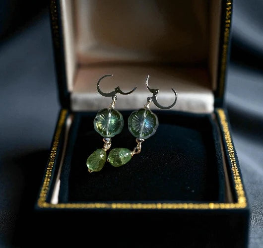 Green gemstone earrings in an open jewelry box