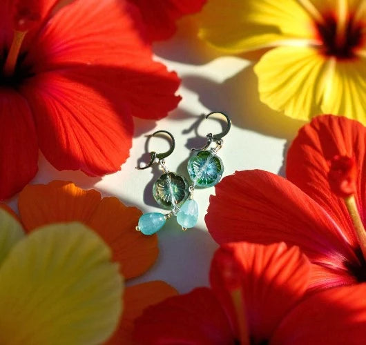 Green earrings with blue stones on a background of red and yellow flowers