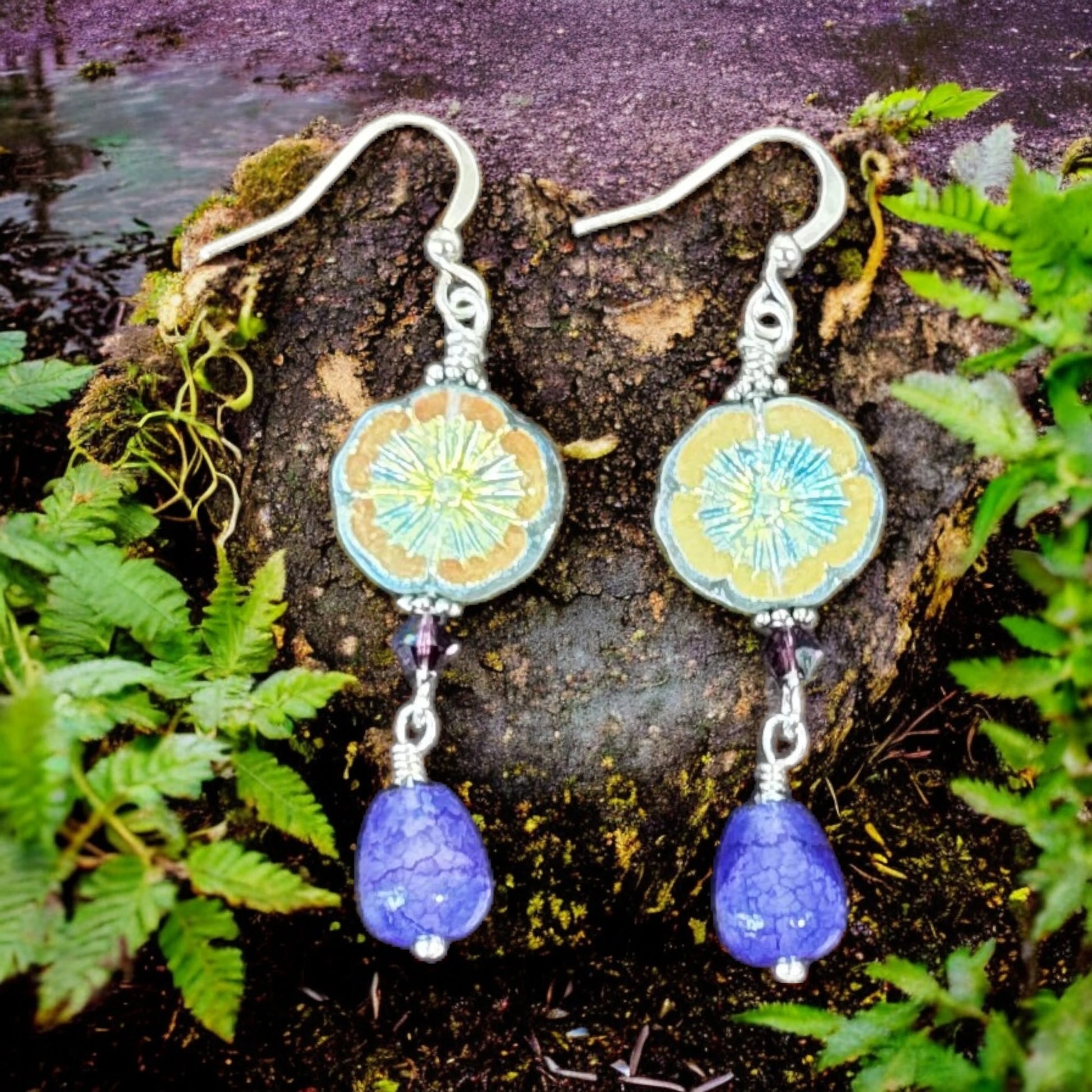Pair of earrings with blue teardrop pendants on a natural background