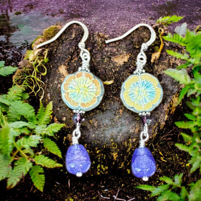 Pair of earrings with blue teardrop pendants on a natural background