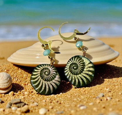 Green spiral earrings with gold accents on a beach setting