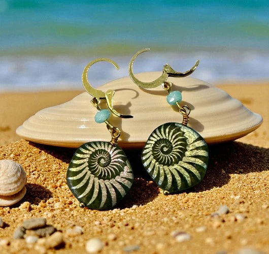 Green spiral earrings with gold accents on a beach setting