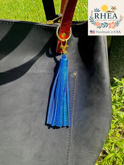 Blue tassel on a black bag with RHEA Artistry Studio branding.