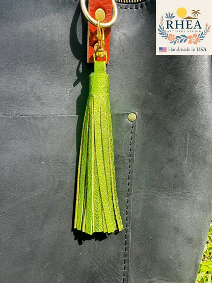 fern Green tassel keychain attached to a leather bag with RHEA branding.