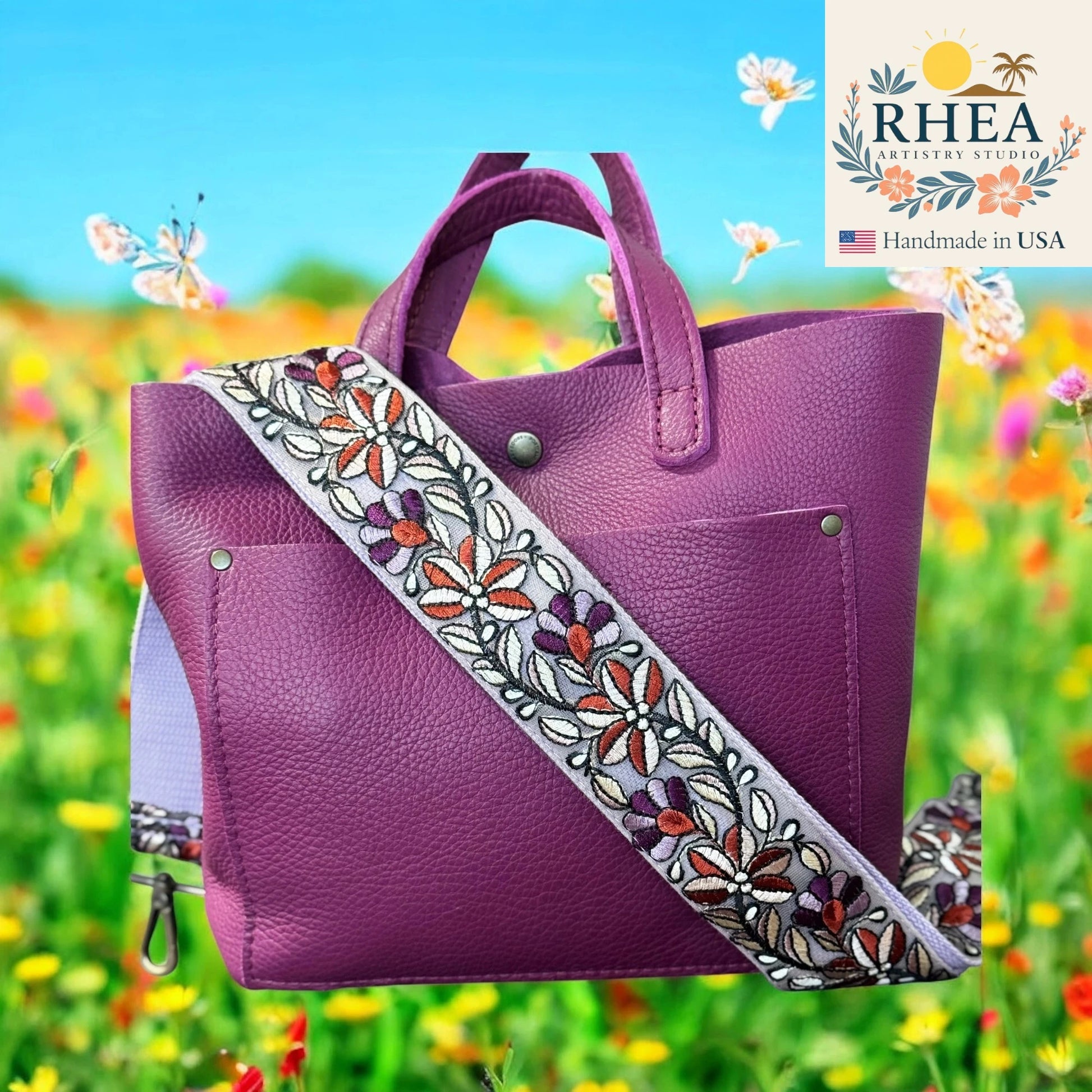 Purple handbag with a floral purse strap against a colorful field background, featuring the RHEEA brand.