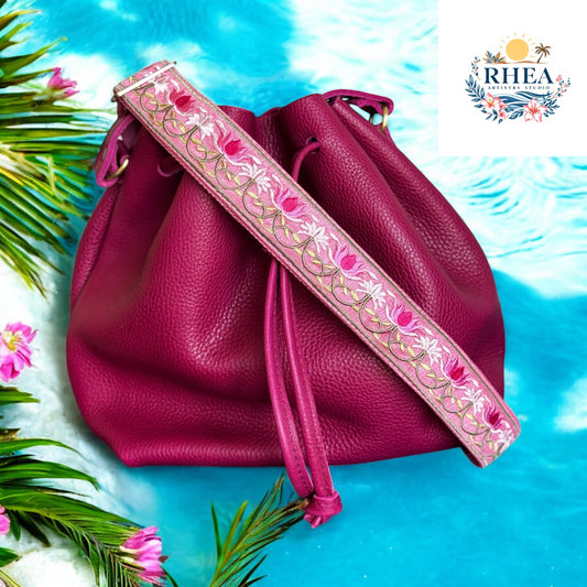 A stunning pink embroidered strap with lotus flower motifs, designed in vibrant pinks and ivory, with leaf vines flowing along a rose-toned cotton webbing at the beach