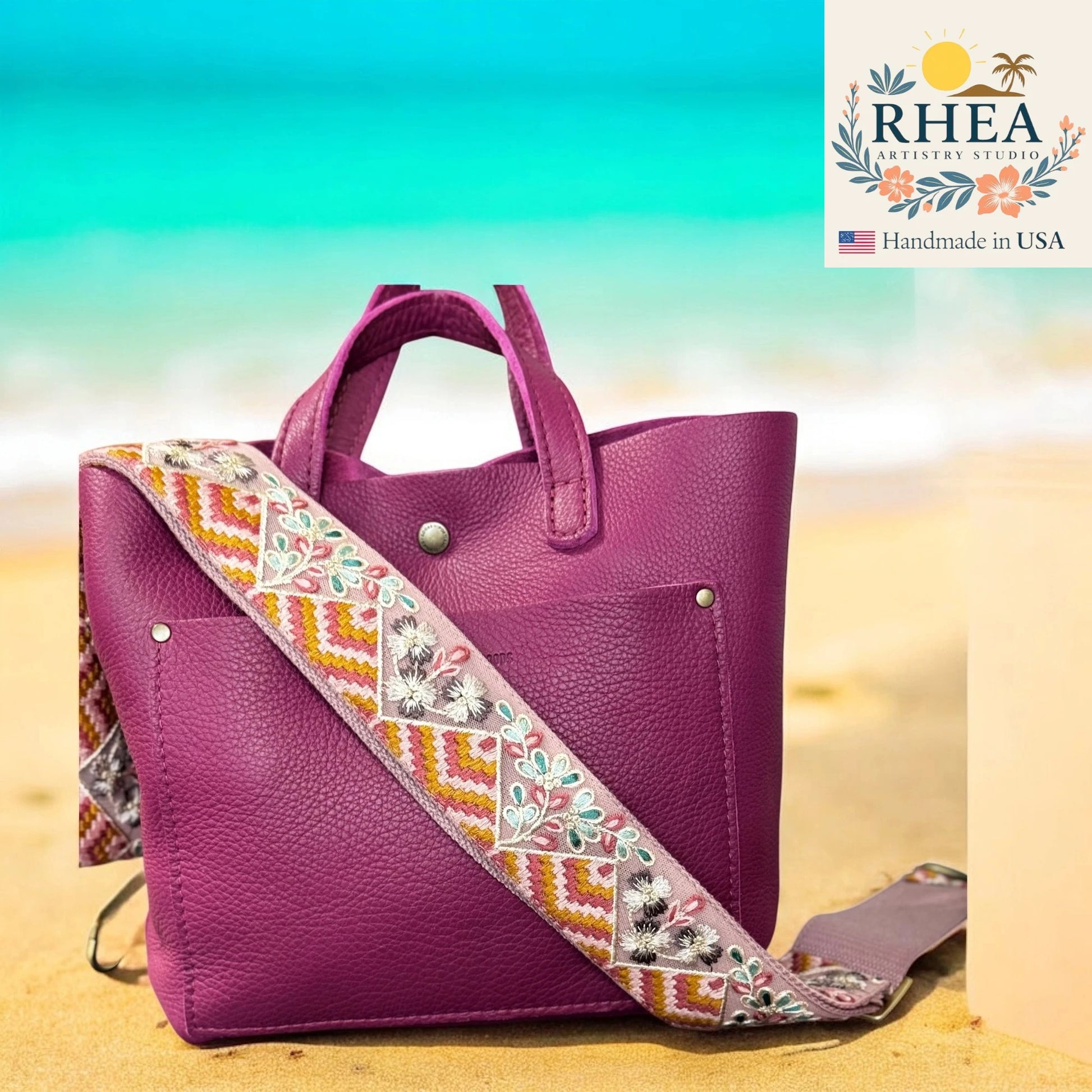 Purple handbag with an embroidered strap on a beach background, featuring the RHEA brand.