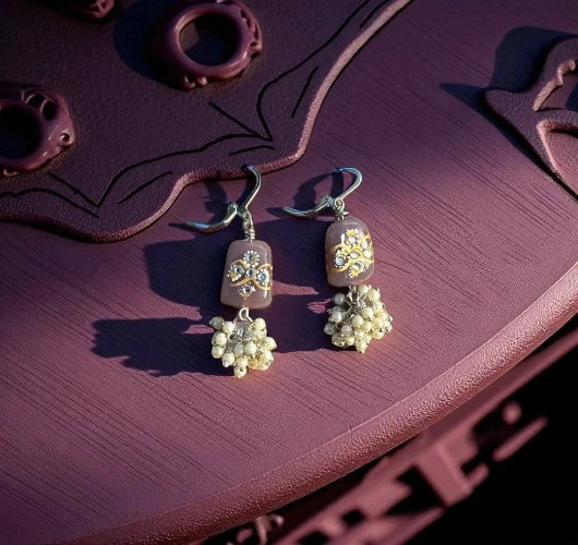 Pair of earrings with floral designs on a purple surface