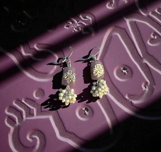 Decorative earrings on a textured purple surface