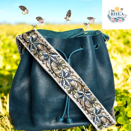 Indigo Garden Trail floral strap on blue leather bucket bag against garden background