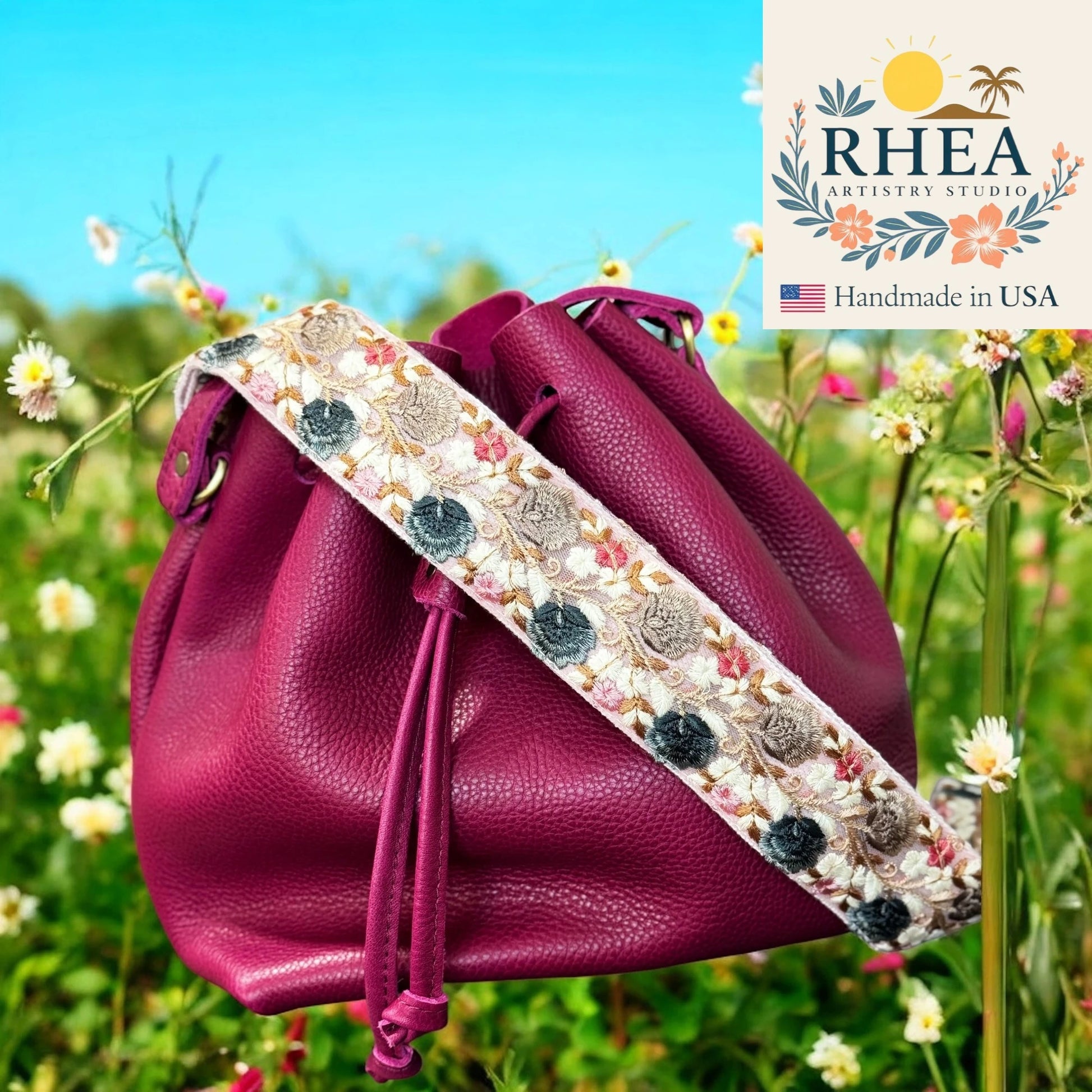 Purple drawstring bag with floral purse strap in a field of flowers, featuring RHEA Artistry Studio logo.