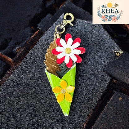 Mini leather bouquet keychain charm featuring red and white daisy, yellow flower, and leaf accents in a green cone wrap