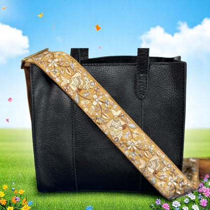 Adjustable embroidered purse strap with floral patterns and gold hardware, displayed on a gray background.