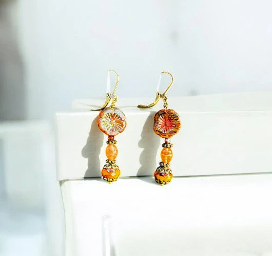 Pair of mustard and gold beaded earrings on a white surface with a light background