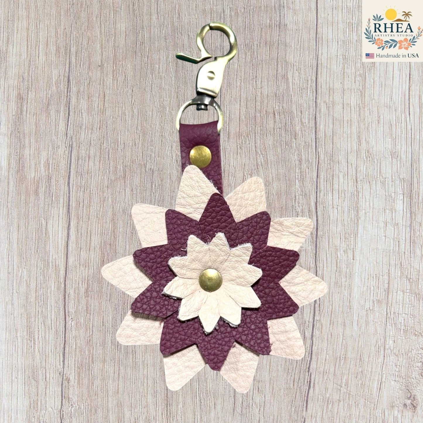 Floral keychain with purple and white flowers on a wooden surface,  Dimensional leather flower charm with natural grain variation