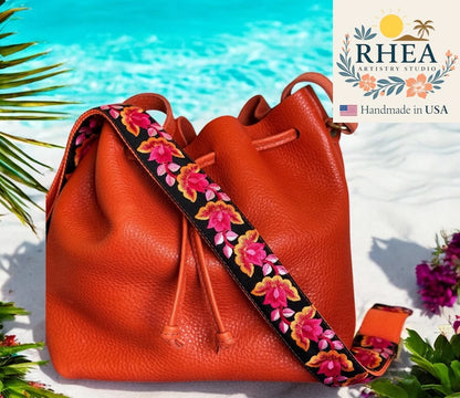 Orange leather bag with floral purse strap by RHEA Artistry Studio on a beach background