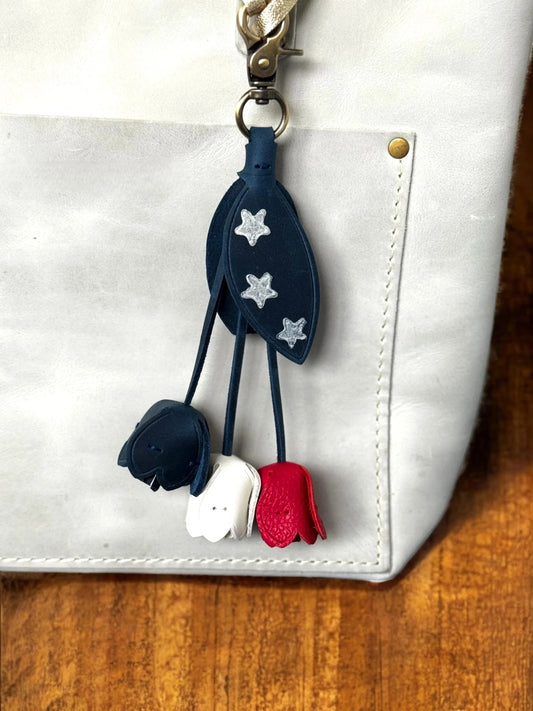 Navy blue keychain with white and red accents attached to a white bag.
