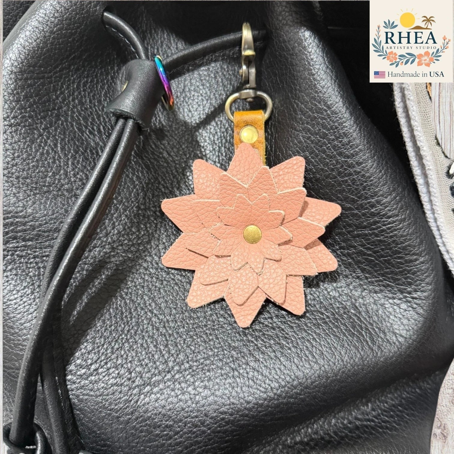 Leather flower keychain on a black leather bag ,Layered leather starflower charm showcasing artisanal craftsmanship