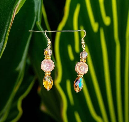 Pair of gold and gemstone earrings on a green leaf background