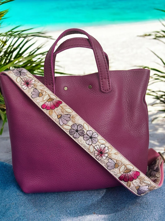 Fuchsia leather tote paired with a pastel embroidered strap featuring plum, beige, and soft rose florals.