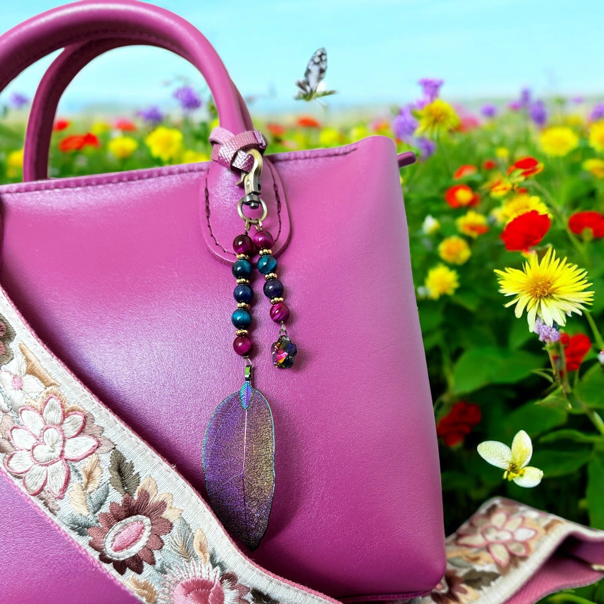 Pink handbag with a decorative charm against a colorful floral background