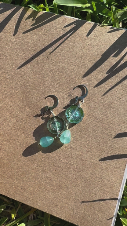 A pair of cathedral-shaped silver drop earrings with light blue colored glass.