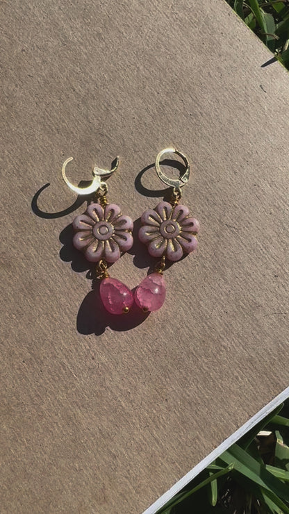 A pair of pale pink daisy-shaped earrings with gold wash and small pink gemstone accents, with gold plated brass findings.