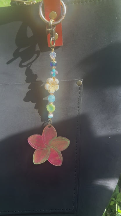 Decorative keychain with colorful beads and a red flower charm on a black bag.