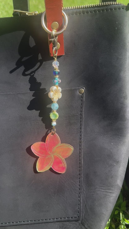 Decorative keychain with colorful beads and a red flower charm on a black bag.