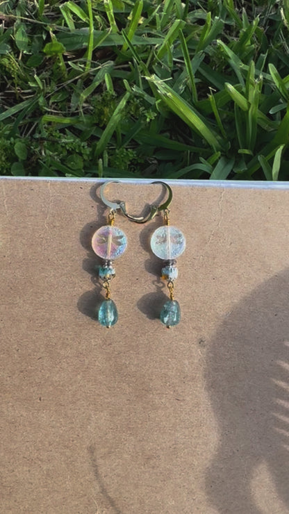 Pair of earrings with green and gold beads on a old book