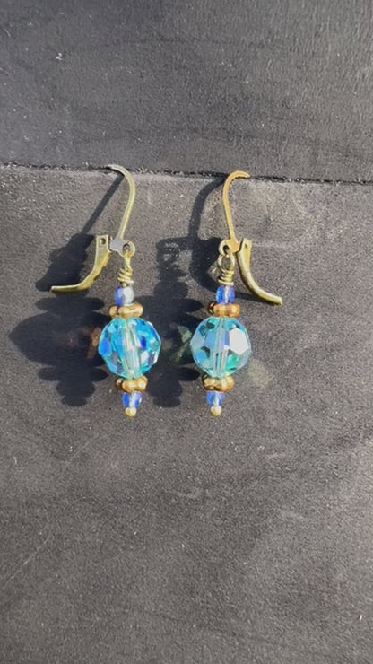 Gold and blue beaded earrings on a black bag