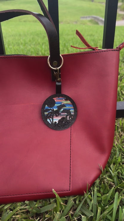 Round leather purse charm with beach scene design on a red background