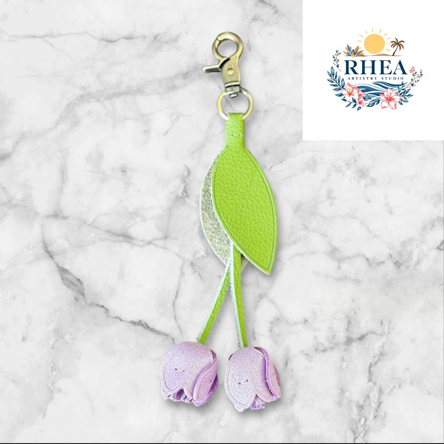 Green and purple keychain on a white surface with grass and flowers in the background