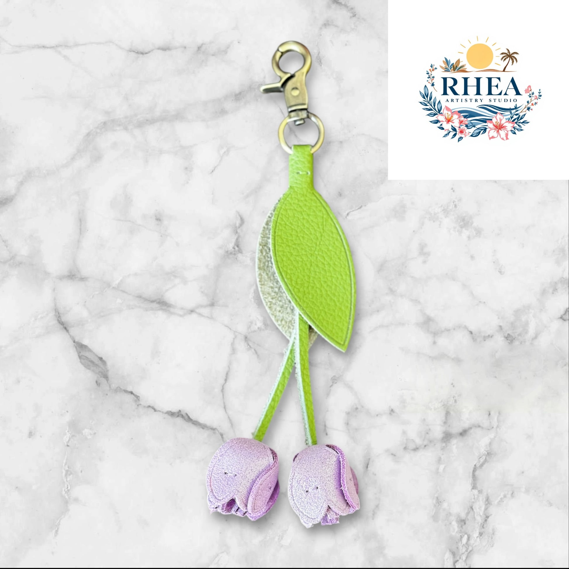 Green and purple keychain on a white surface with grass and flowers in the background