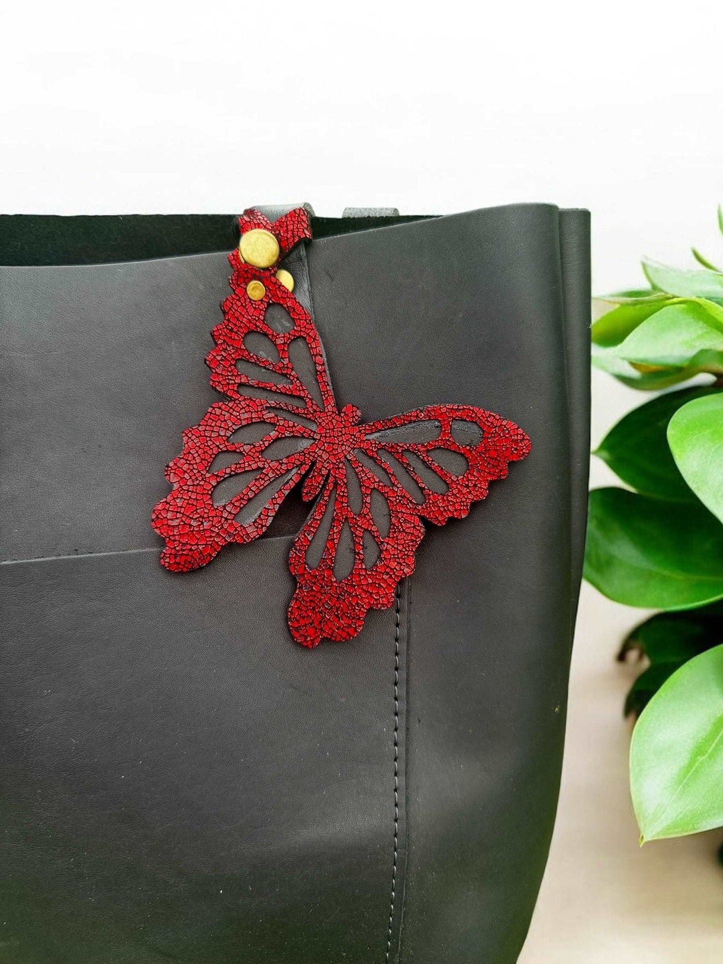 Handcrafted leather butterfly charm in a vibrant crackled red finish with halo metallic leather and a crackled texture, featuring a snap closure for easy attachment to accessories.