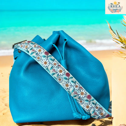 Blue leather bag with floral strap on a beach