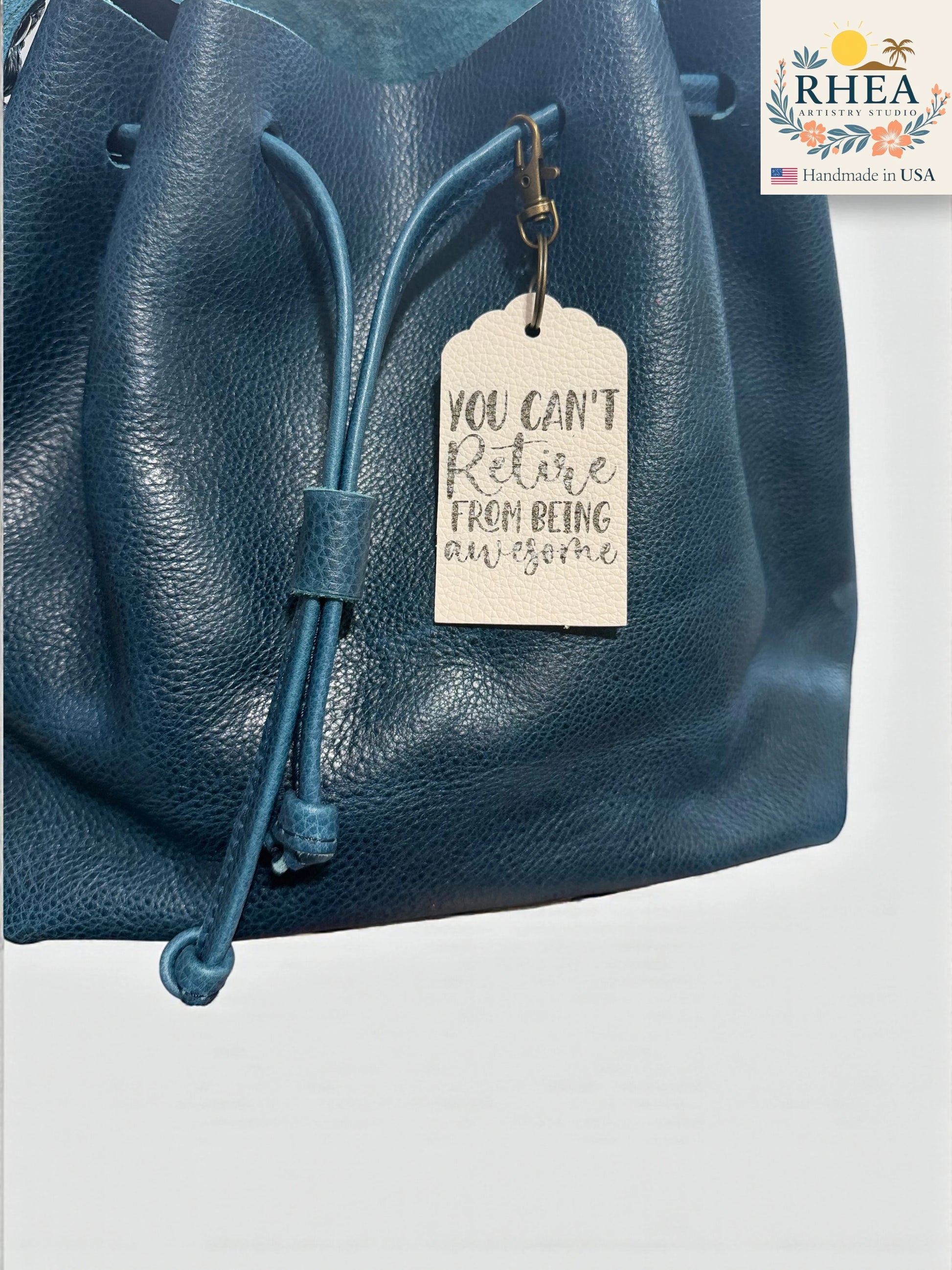 Blue leather bag with a motivational tag and RHEEA brand logo.
