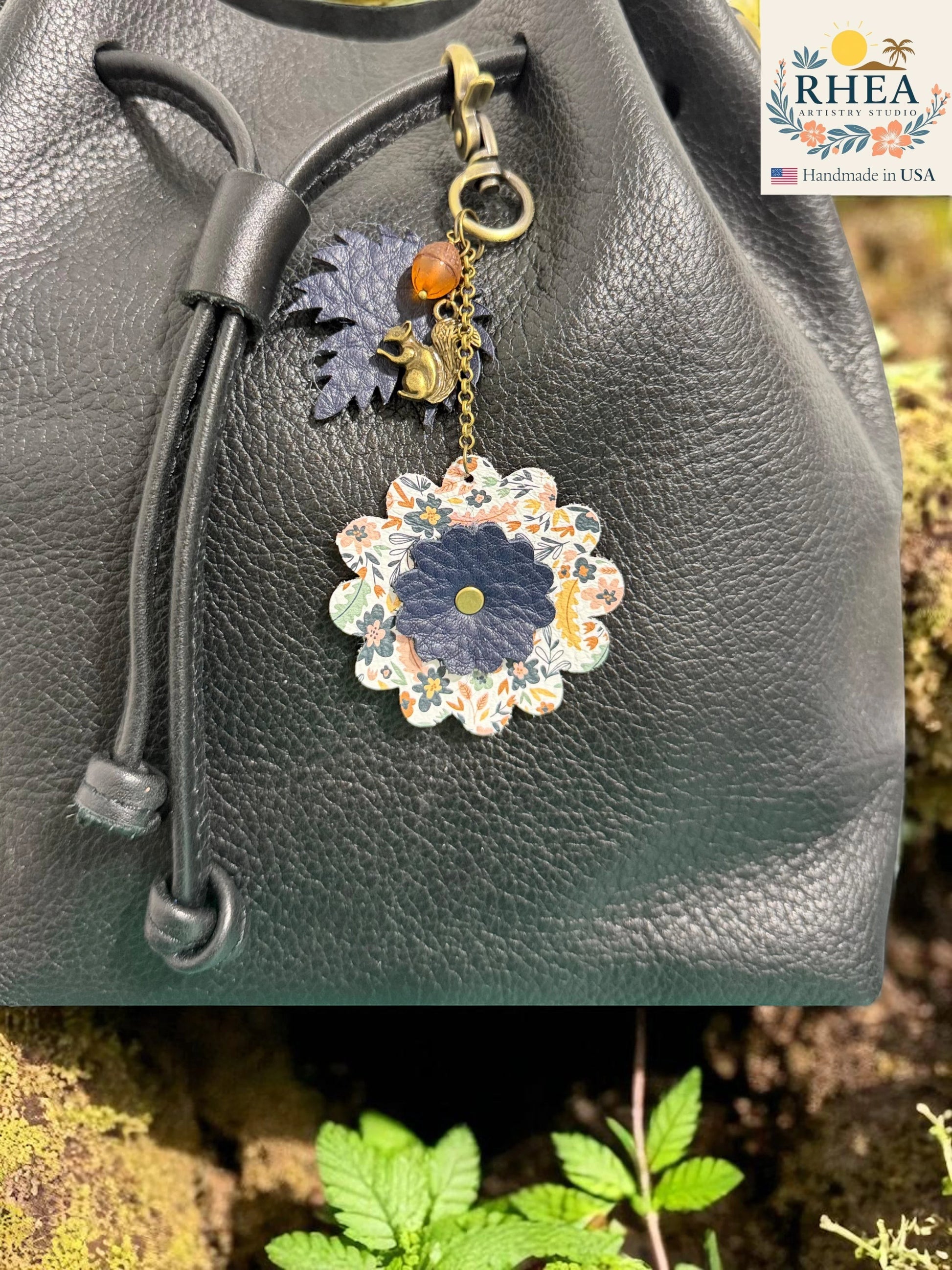 Rhea Artistry Studio Acorn Tales leather charm collection features a floral leather flower, acorn, and squirrel charm on a black leather bag.