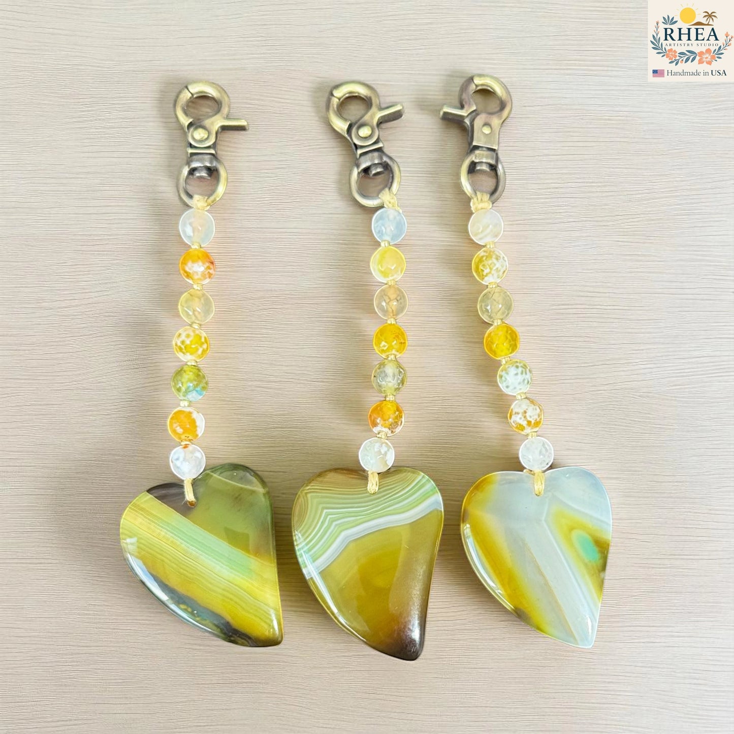 Rhea Artistry Studio handmade agate heart bag charm with yellow, green, and white natural gemstone beads and brushed brass clasp.