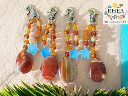 Rhea Artistry Studio handmade agate and moonstone star bag charm with teardrop pendant. Warm orange, yellow, and red beads.