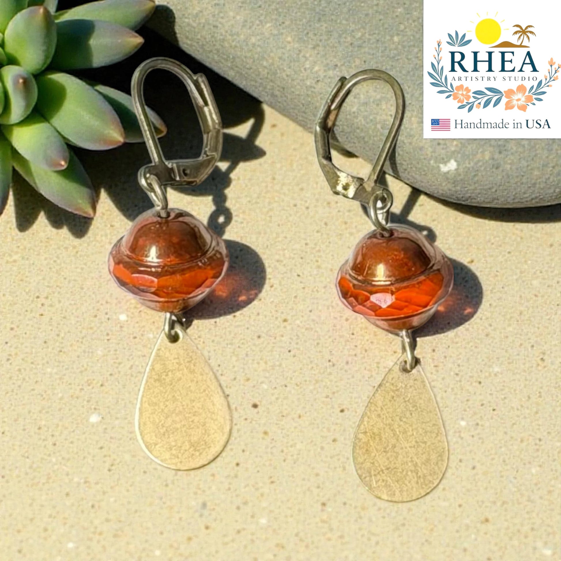 Rhea Artistry Studio handcrafted drop earrings with faceted amber glass beads and brushed brass teardrops, 2 inches long.