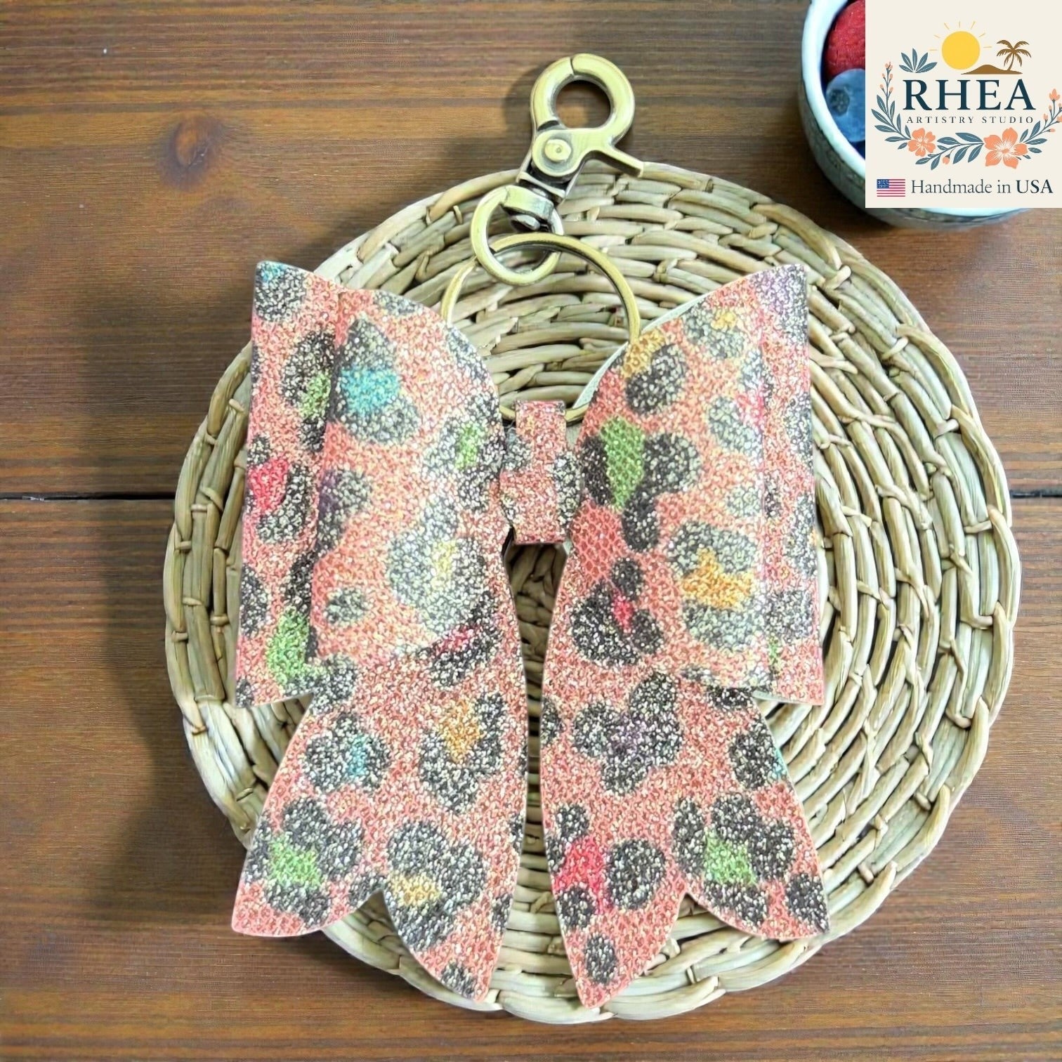 Rhea Artistry Studio handmade animal print bow bag charm with brass hardware and holographic finish.