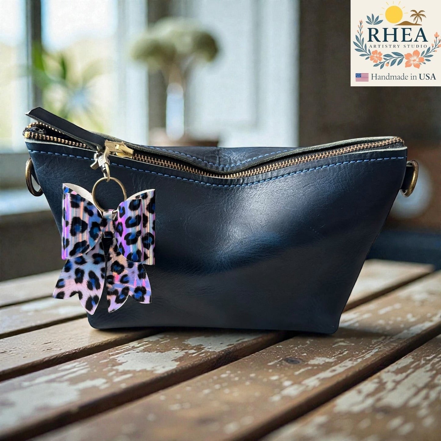 Rhea Artistry Studio handmade animal print bow bag charm with holographic finish and brass hardware.
