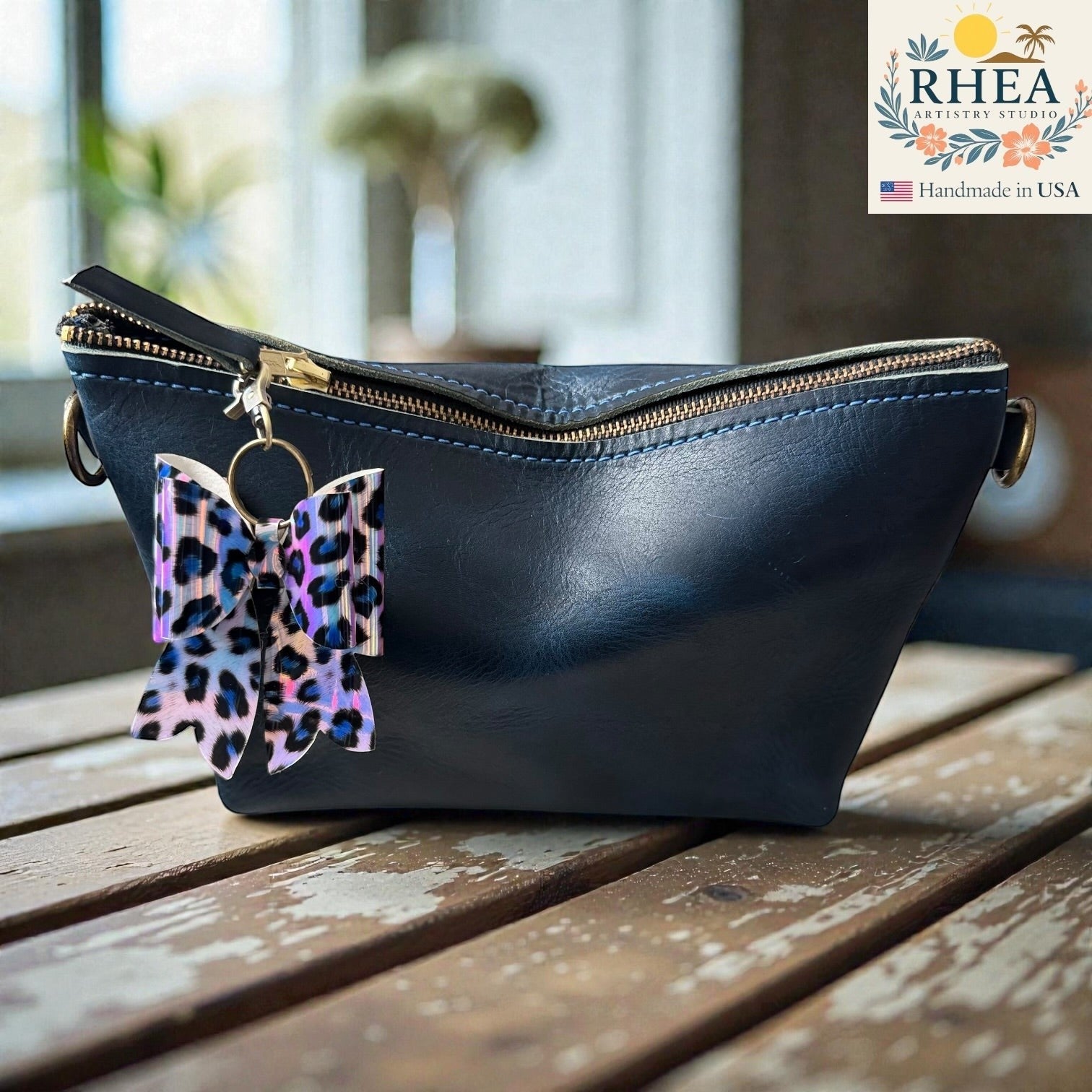 Rhea Artistry Studio handmade animal print bow bag charm with holographic finish and brass hardware.