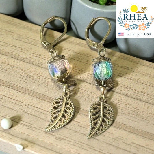 Rhea Artistry Studio antique brass leaf drop earrings with iridescent faceted glass beads, 2 inches long.